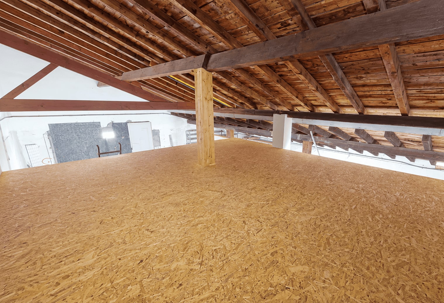 Mezzanine terminée : plancher OSB continu sur toute la surface, sous charpente.