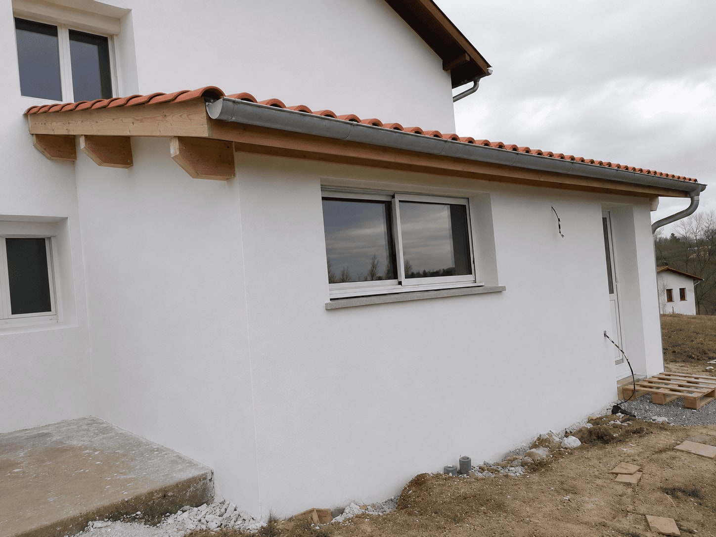 Extension terminée vue de l’extérieur : toiture en tuiles et débord de toit finis.