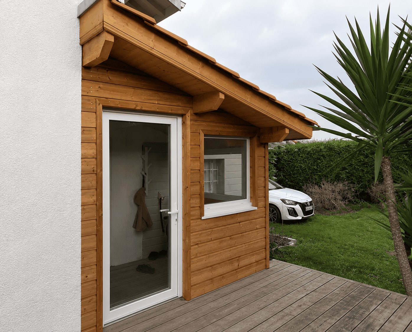 Façade d’extension habillée de lames de bois horizontales, avec débord de toit et gouttière.