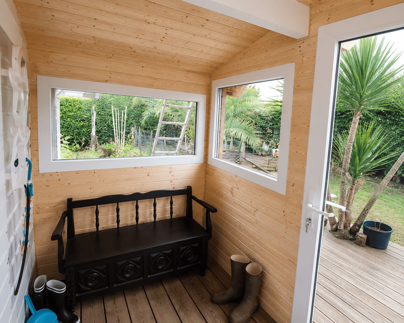 Intérieur de l’extension : parois et plafond en bois, deux ouvertures sur le jardin.